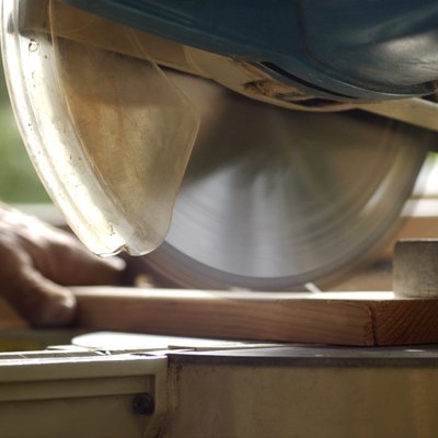 Close-up of circular saw blade in motion as a man is about to cut a piece of wood.