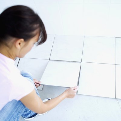 Young woman laying floor tiles