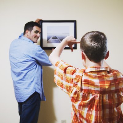 Son helping father straighten picture