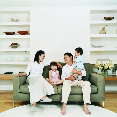 Smiling Family of Four Sitting on a Sofa in a Living Room
