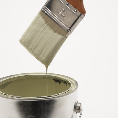 Paint running off paintbrush into paint can