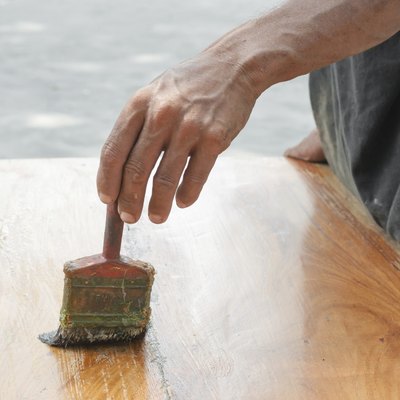 Varnishing antique wooden table  using paintbrush