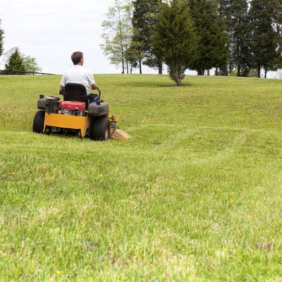 Senior man rides zero turn lawn mower on turf