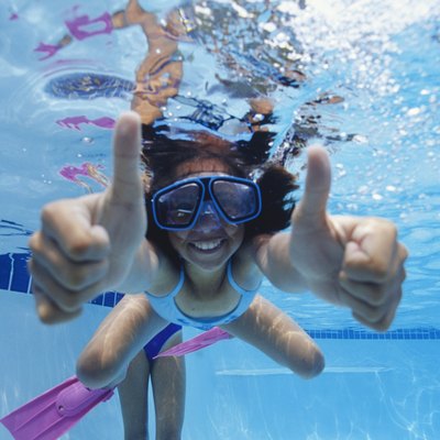 Girl (8-9) swimming underwater, showing thumbs up, underwater view