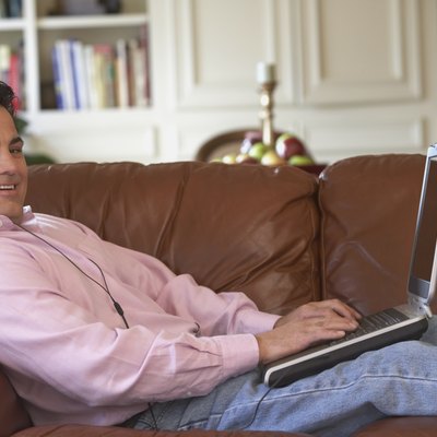 Portrait of a mid adult man lying on a couch working on a laptop