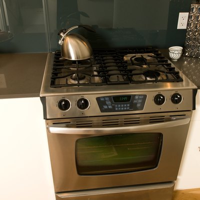 Stovetop and oven by a tray of fruit on the counter