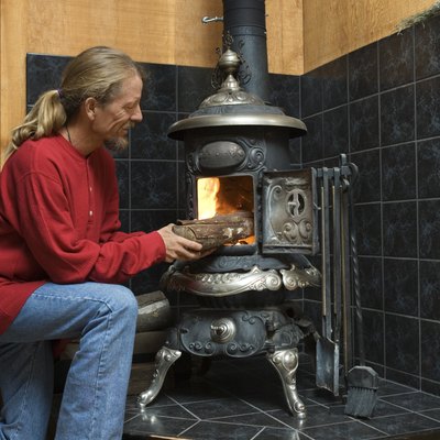 Man putting firewood into wood stove
