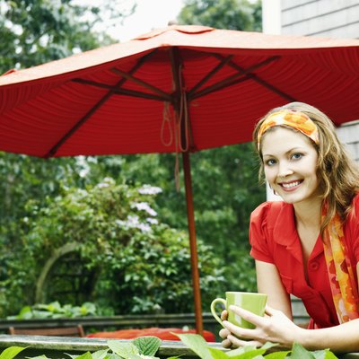 Smiling woman with coffee by patio umbrella