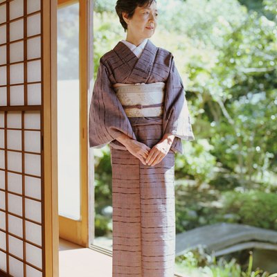 Senior woman in kimono standing in open doorway, looking away