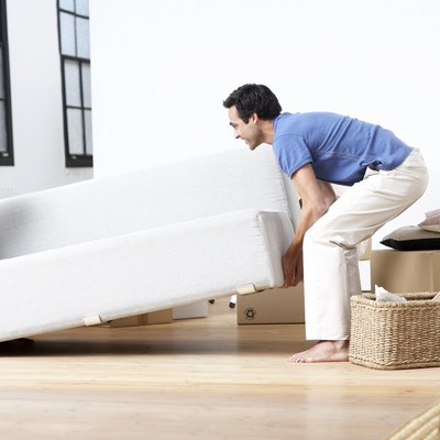Couple lifting sofa, smiling, side view