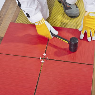 Worker Applies with Rubber Hummer Tile on a wooden Floor