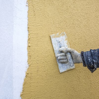 trowel with glove hand plastering a wall