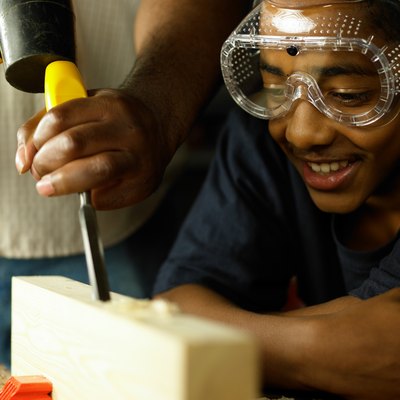 Teenager watching wood being chiselled