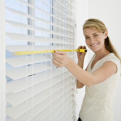 Woman measuring window blinds