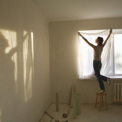 Woman fitting curtains in new apartment