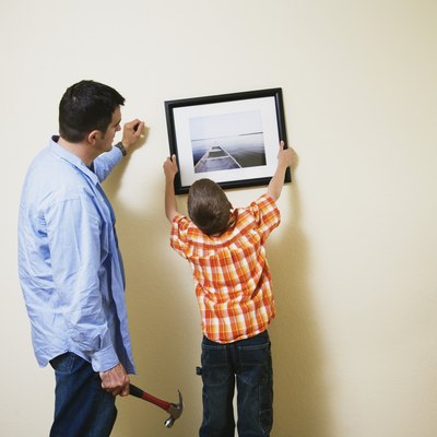 Father and son hanging picture together