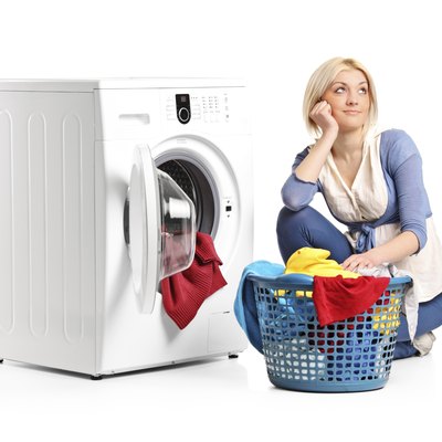 Woman in thoughts seated next to a washing machine