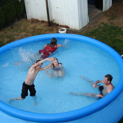 Kids playing in a soft-side above-ground swimming pool.
