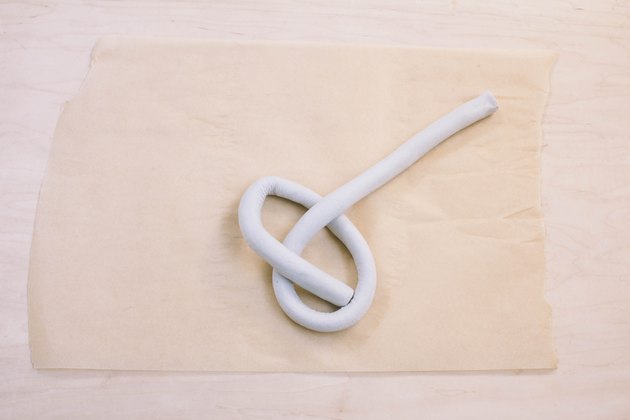 Shaping tube of air dry clay into a knot