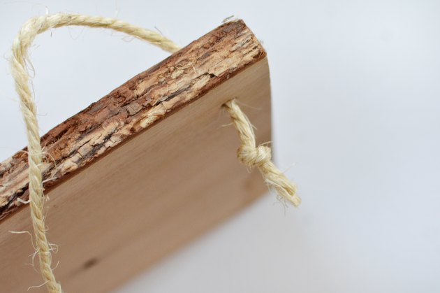 Morceau de bois avec un bord de grain avec une corde enfilée avec un noeud à la fin