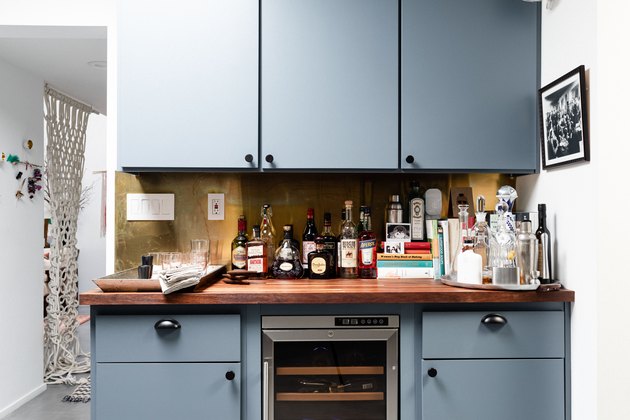 focus on bank of blue cabinets with butcher block counter and wine fridge