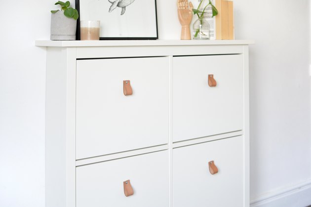 Ikea shoe storage with leather pull handles. Small trinkets styled on top including candles, plants and pictures.