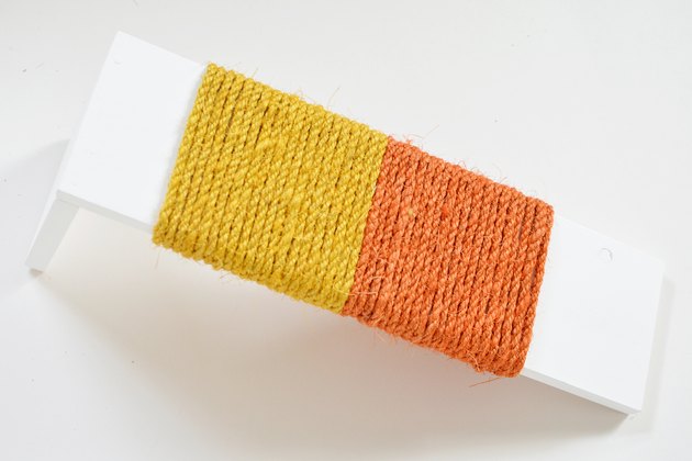 Yellow and orange sisal rope wrapped around white wood for DIY cat scratching post