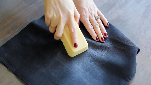 Rubbing bar of fabric wax into canvas fabric