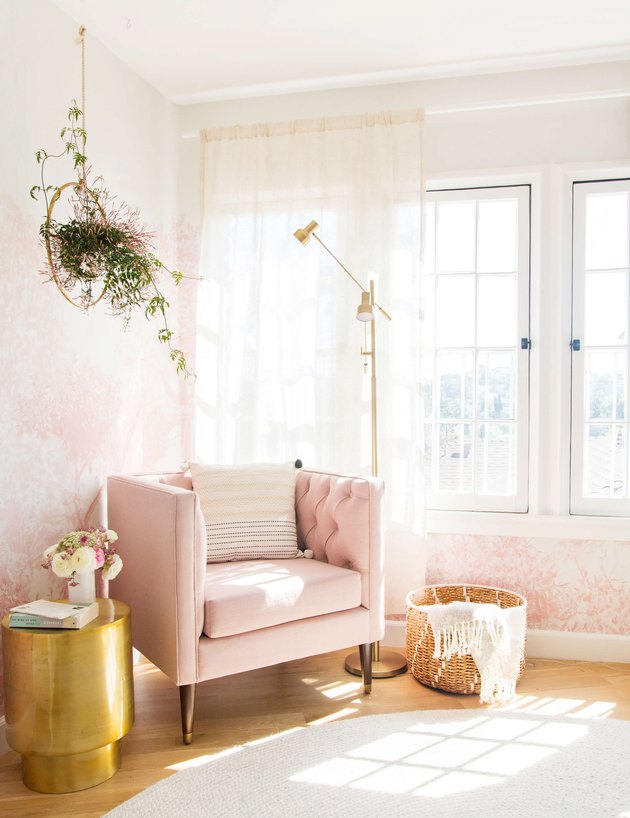 pink living room with wallpaper and velvet lounge chair