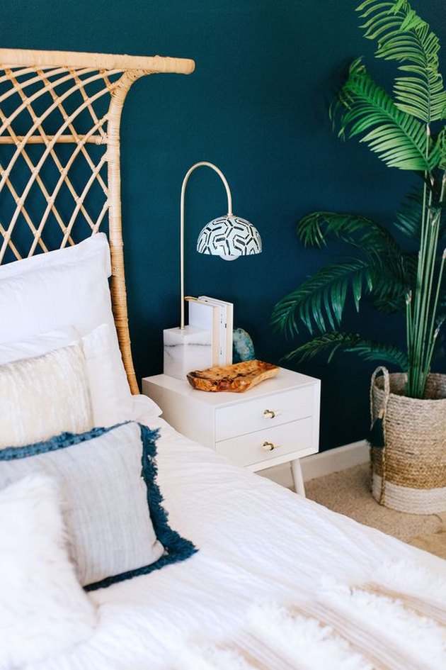 сине-зеленая спальня с тканым изголовьем и растением в горшке