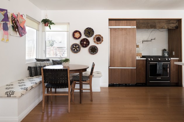 Dining room and kitchen with benches, a round wood table and hardwood floor