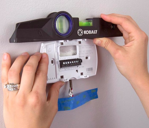 Programmable thermostat being installed.