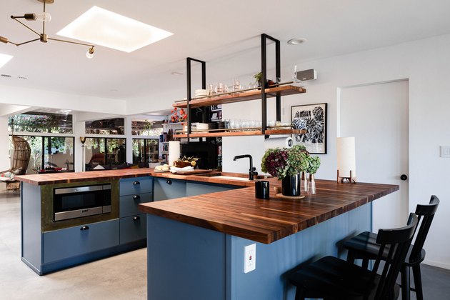 open concept kitchen with blue kitchen island and concrete flooring