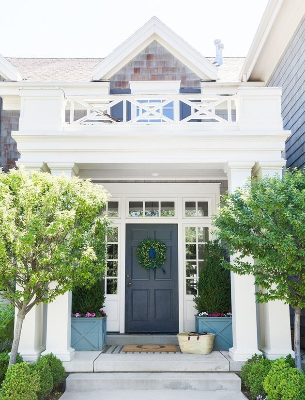 Farmhouse front door idea in navy with boxwood wreath and topiaries