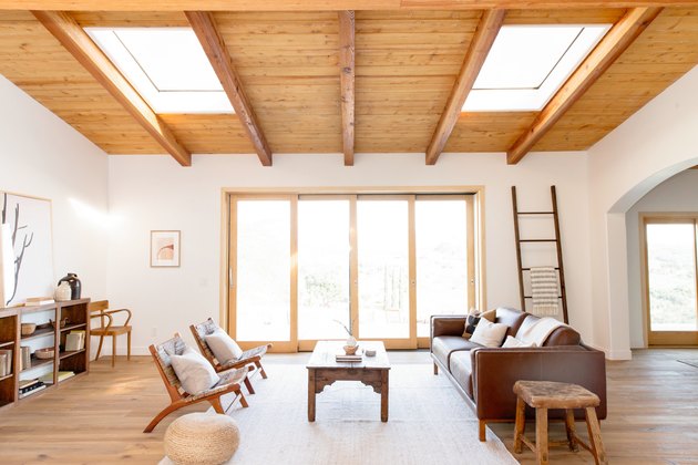 large open living space with blanket ladder, chairs, sofa, doors that lead outside