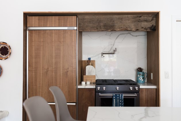 focus on stove with wood cabinet surround, marble backsplash, pot fillerf aucet