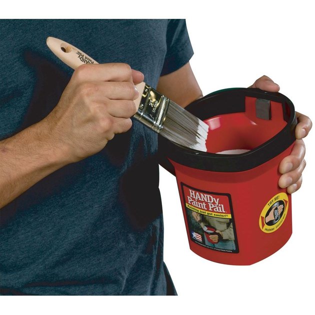 Dipping paint brush in paint container.