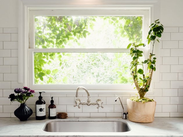 view of kitchen sink, double handle faucet and window with view of greenery