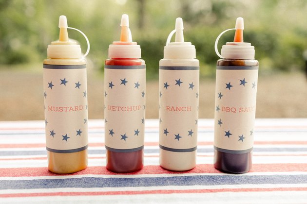 Four hot dog bar condiment bottles with printable labels for mustard, ketchup, ranch, and BBQ sauce