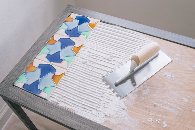 Tiles pressed into adhesive which has been scraped with a notched trowel