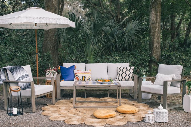 DIY tiled coffee table in in outdoor patio with colorful pillows, fringe umbrella and round woven rug