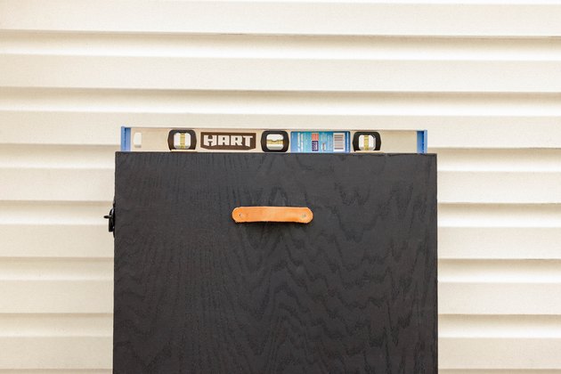 Cabinet held against wall with level on top to check for levelness