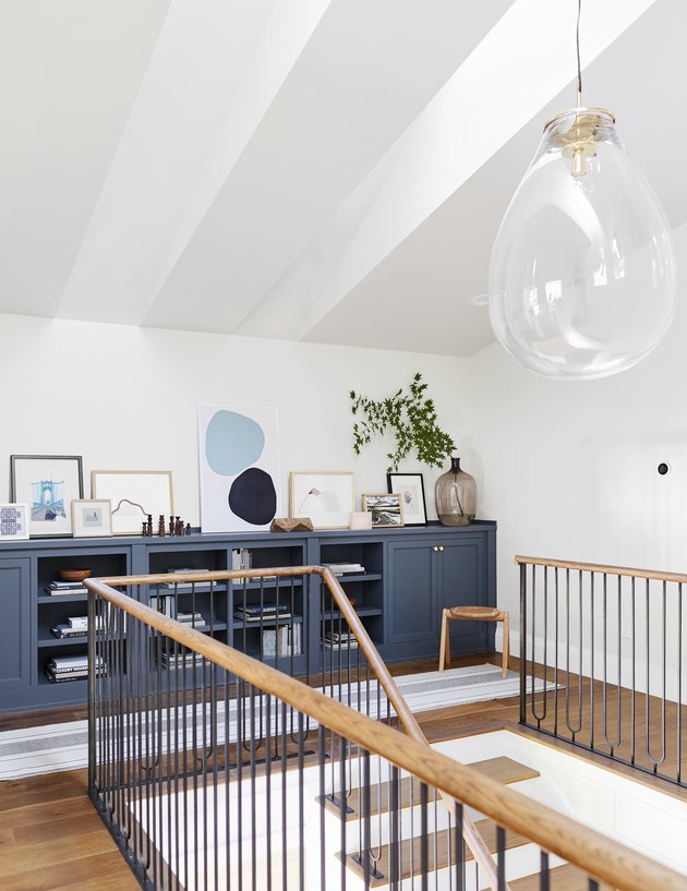 Blue bookshelf with glass pendant light and art leaning against wall
