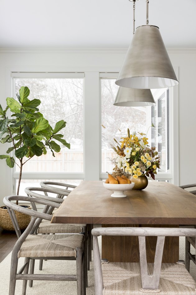 Dining table with potted tree near window and hanging pendant lights