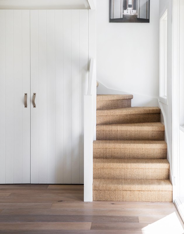 idée de tapis d'escalier en sisal dans une entrée blanche avec des fenêtres