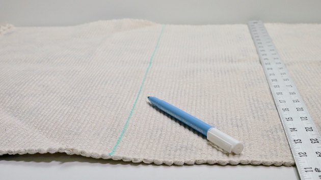 Marking a cut line on a rug for DIY Fringe Pillow project