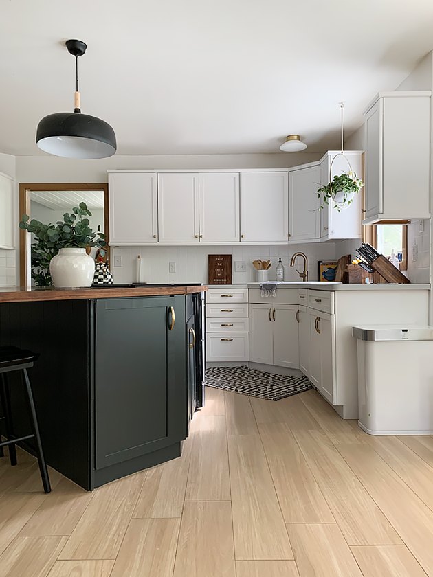 black kitchen cabinet idea for mostly white kitchen with a black island featuring a walnut countertop situated at an angle under a black pendant light