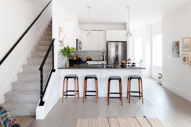 small kitchen next to stairs with peninsula and dark countertops