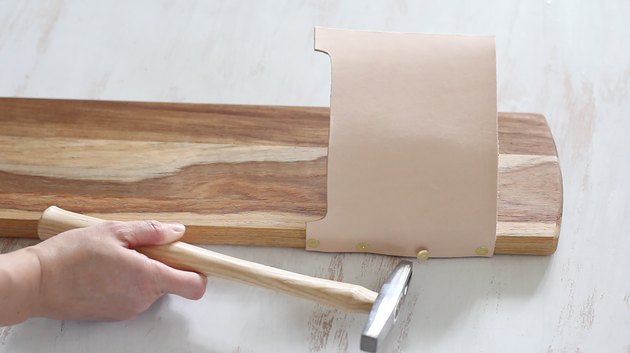 Hammering tacks into the leather pouch