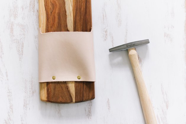 Leather pouch attached to cutting board with brass tacks